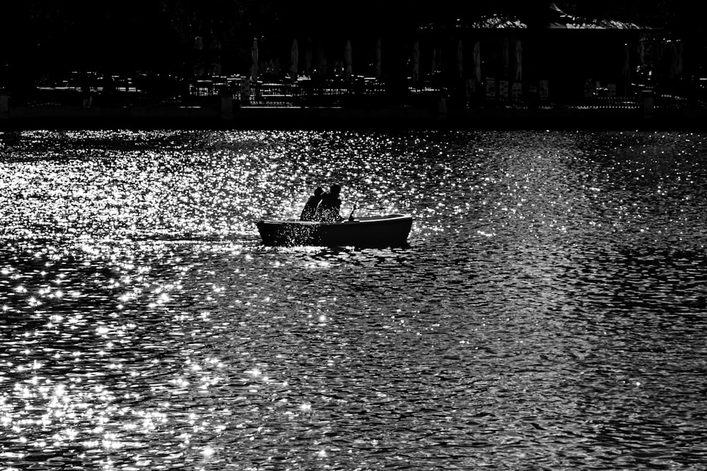 grayscale photo of man riding on boat on water