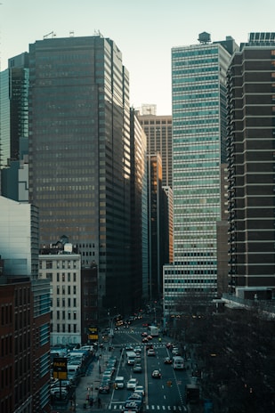 cars on road in between high rise buildings during daytime