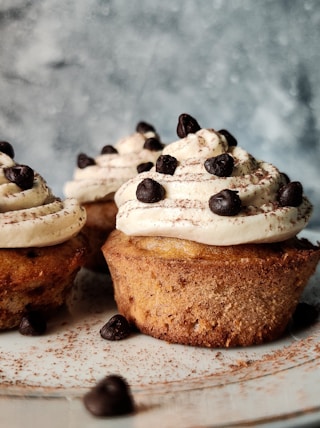 brown and white cupcake with white icing on white ceramic plate