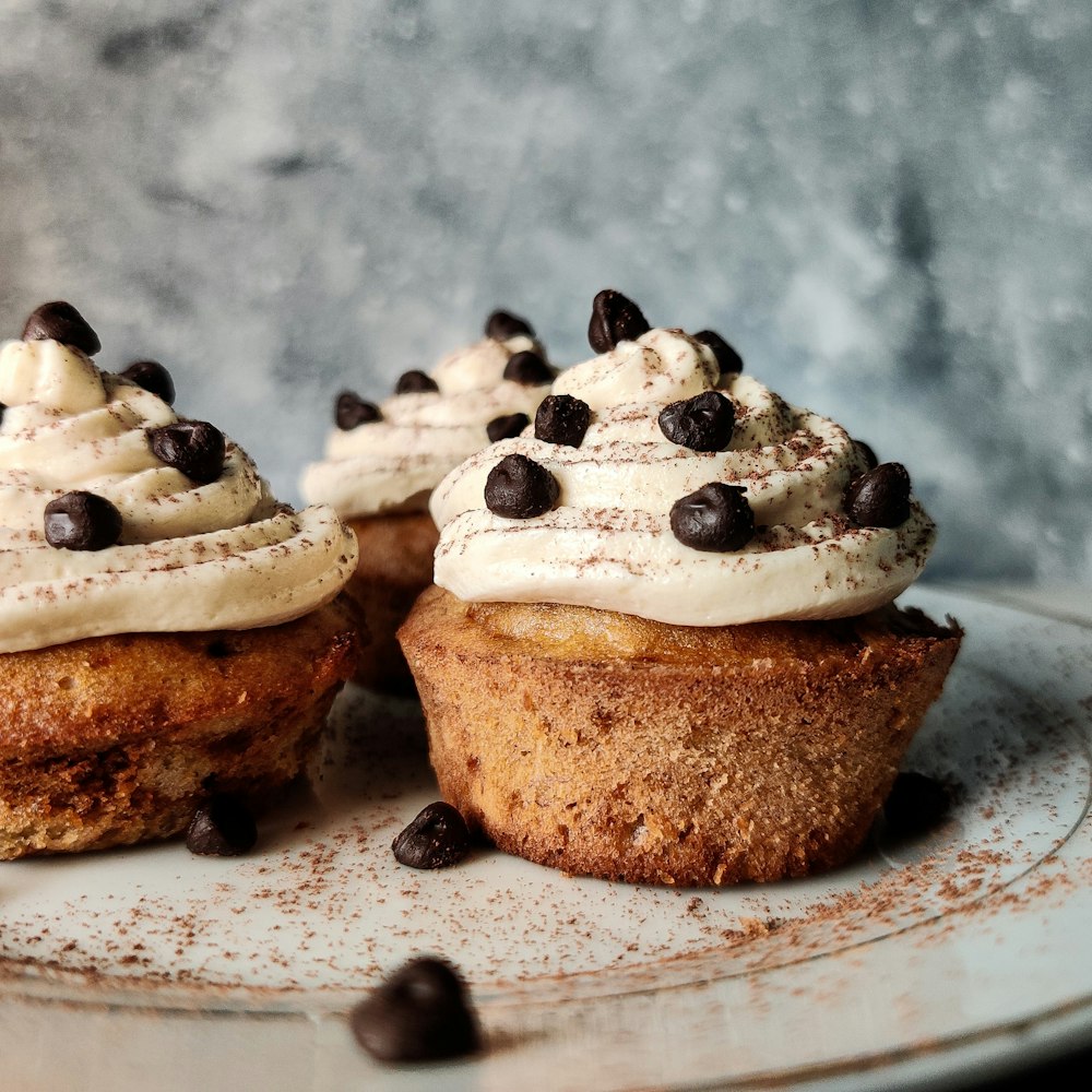 Cupcake marrón y blanco con glaseado blanco en plato de cerámica blanca