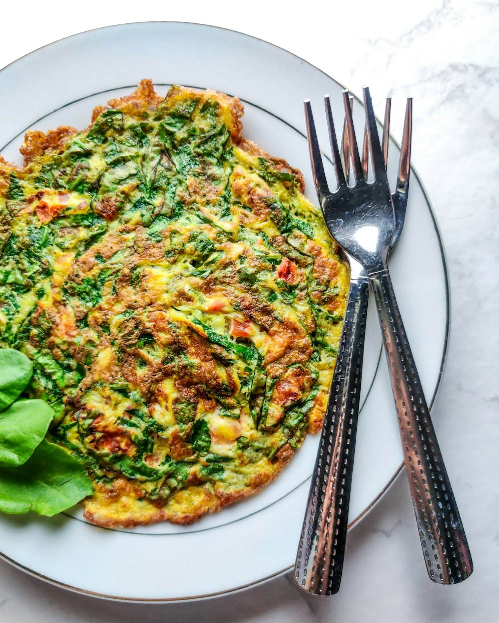 pizza with green vegetable on white ceramic plate