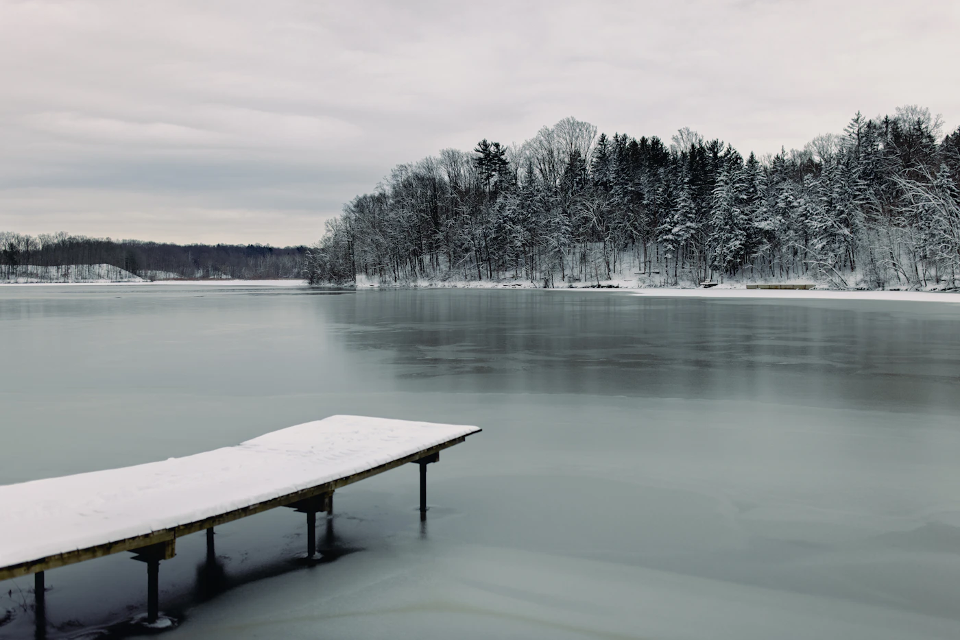 Snow-covered wooden dock on a frozen lake in winter