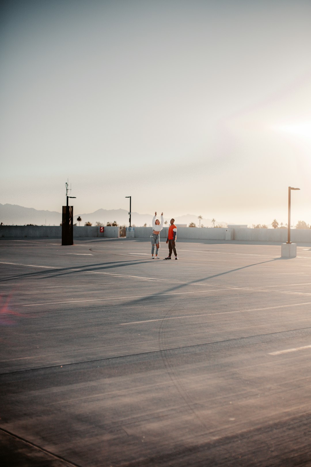 man in red shirt and black pants standing on gray concrete floor during daytime