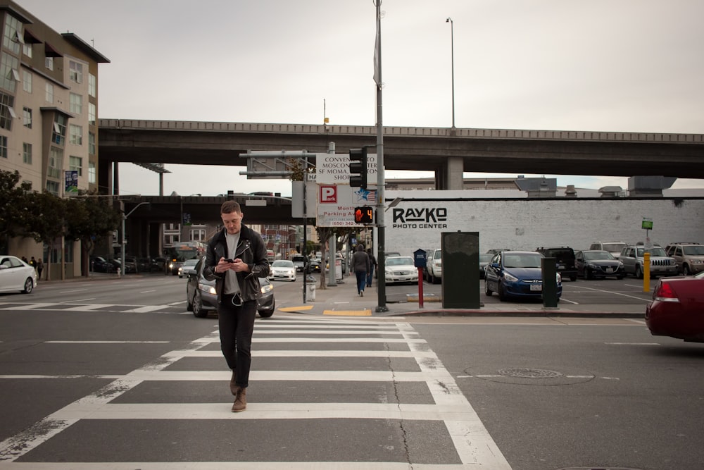 man in black jacket and black pants walking on sidewalk during daytime