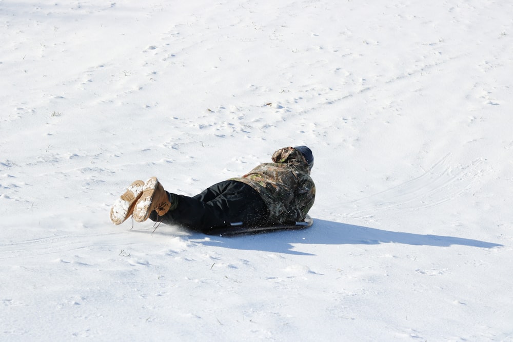 person in black jacket lying on snow covered ground during daytime