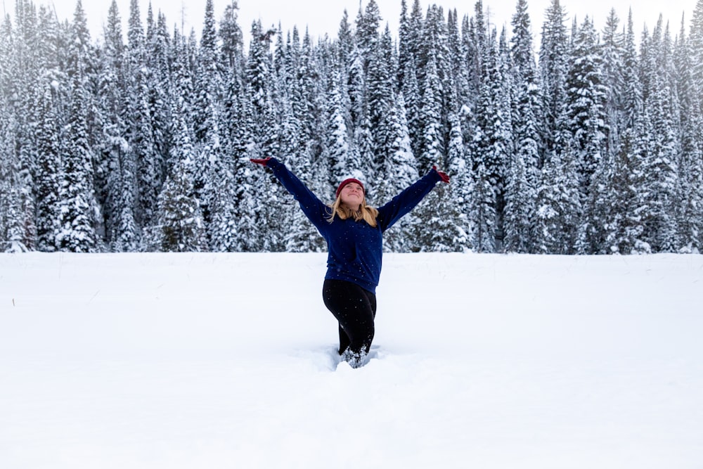 woman in blue jacket and black pants standing on snow covered ground during daytime