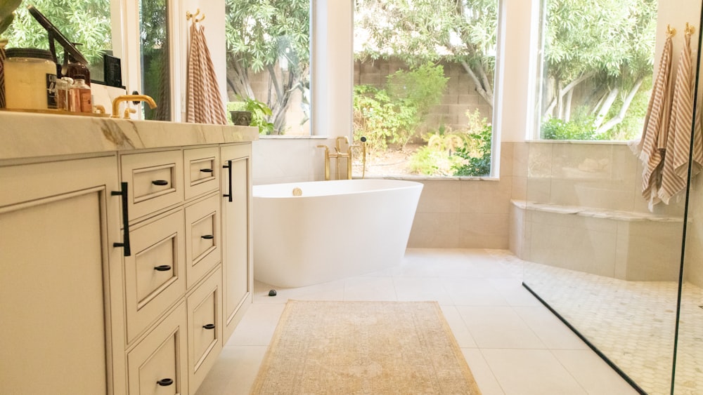 white ceramic bathtub near white wooden cabinet