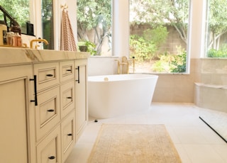 white ceramic bathtub near white wooden cabinet