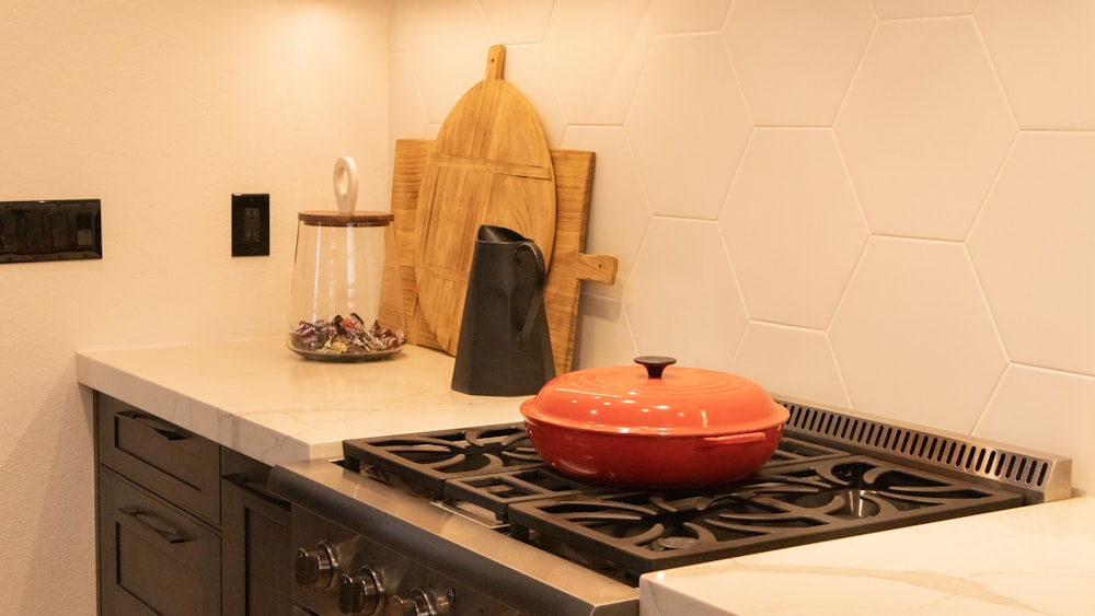 red ceramic bowl on black and white gas stove