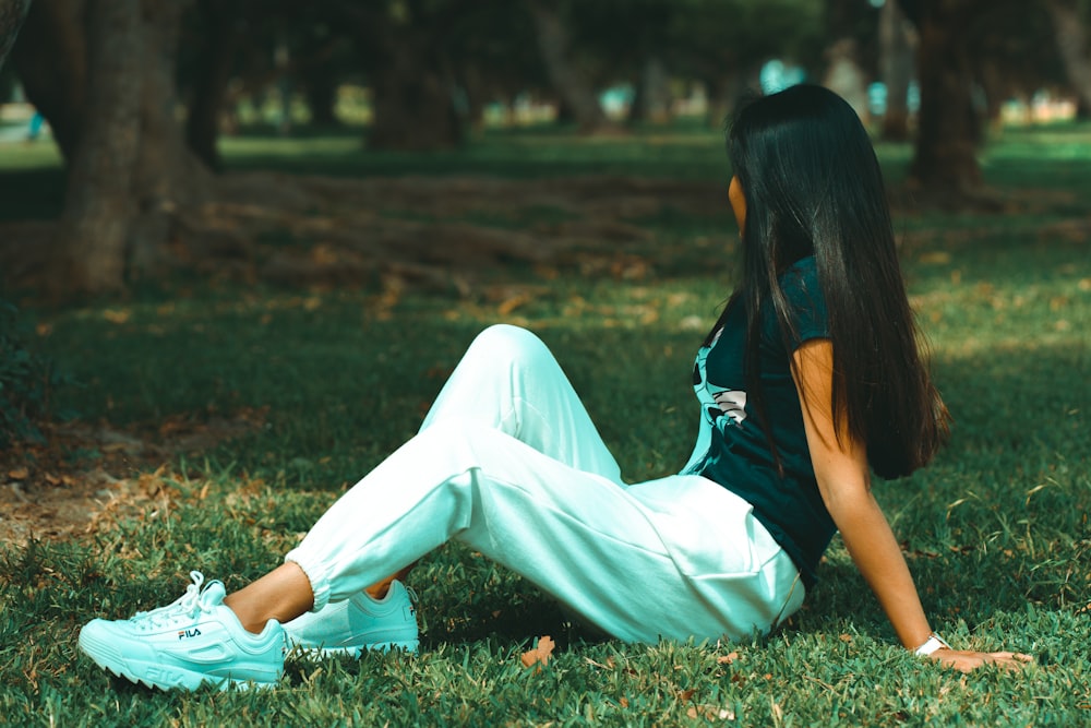 woman in black shirt and white pants sitting on green grass field
