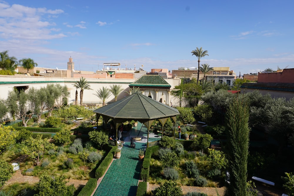 green and white patio umbrella near green trees and brown building during daytime