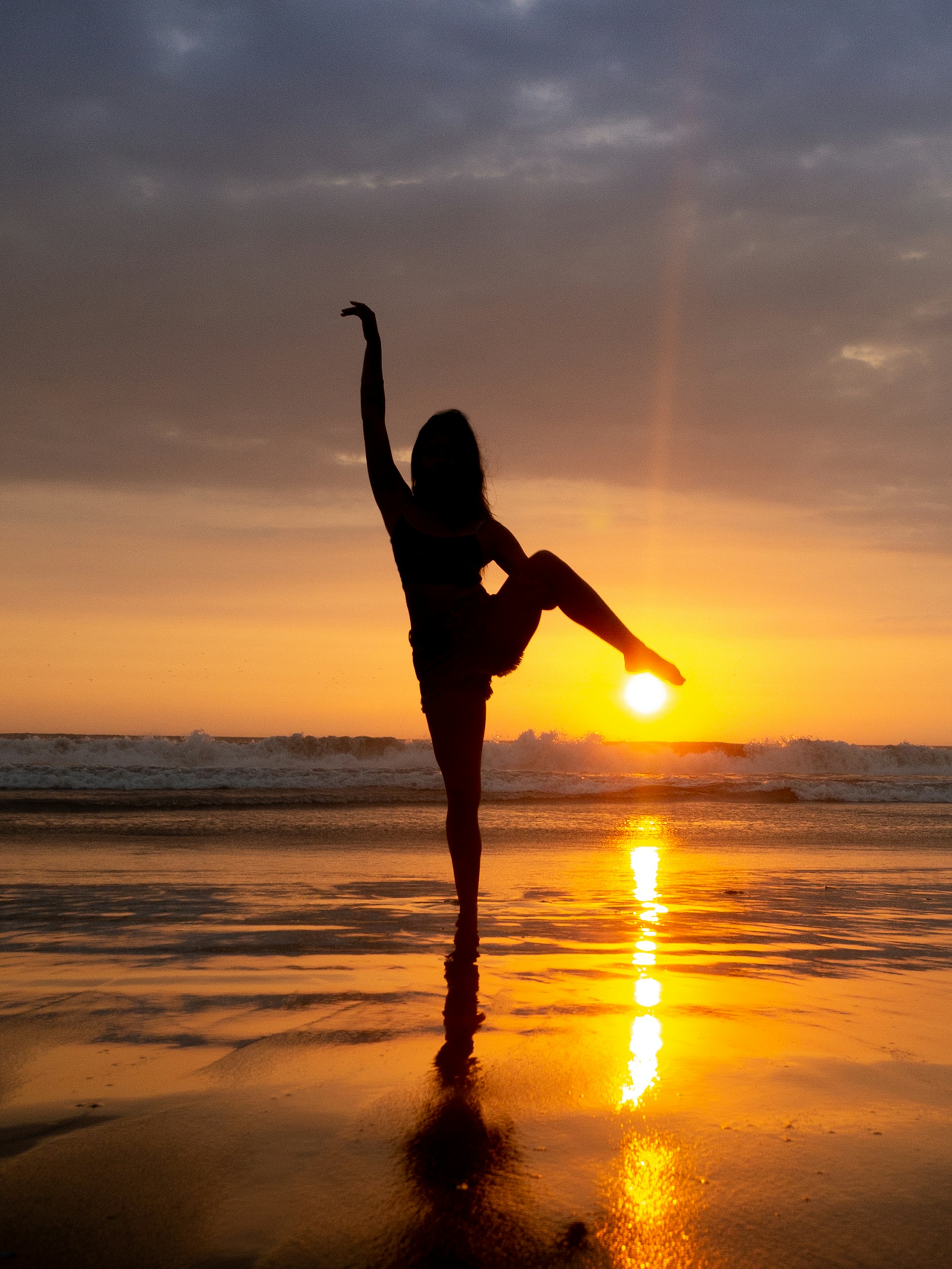 silhouette of woman jumping on beach during sunset