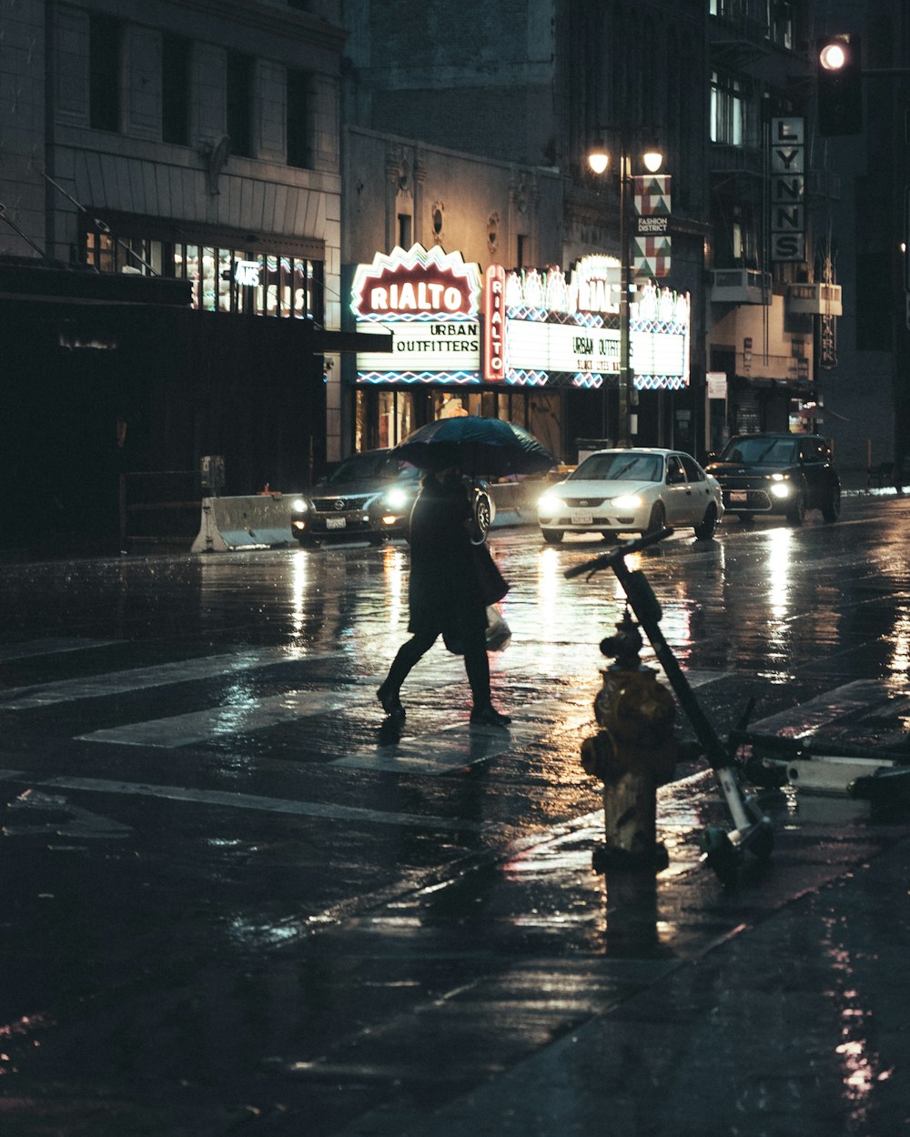 person in black jacket holding umbrella walking on sidewalk during night time