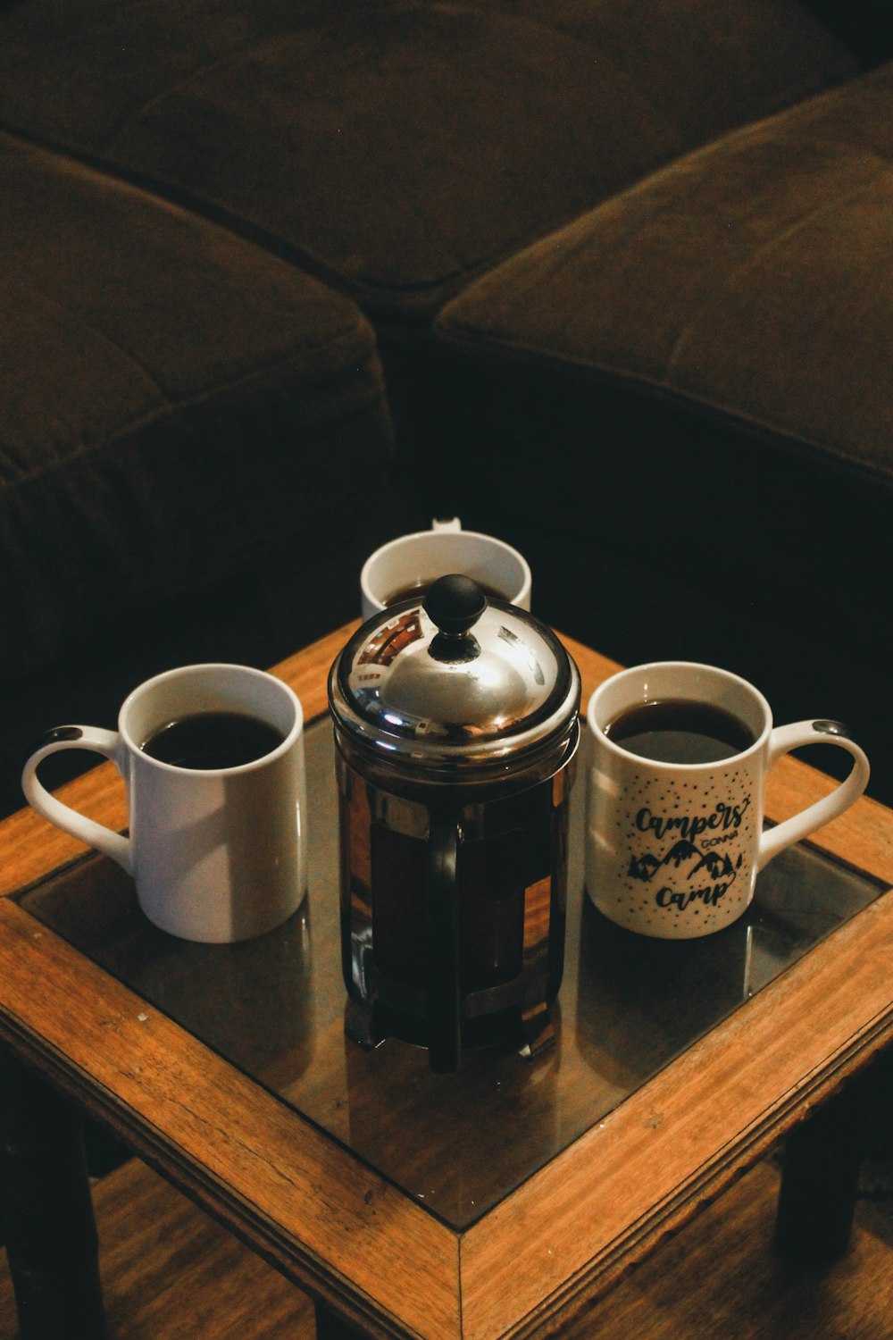 white ceramic mug beside stainless steel teapot on brown wooden table