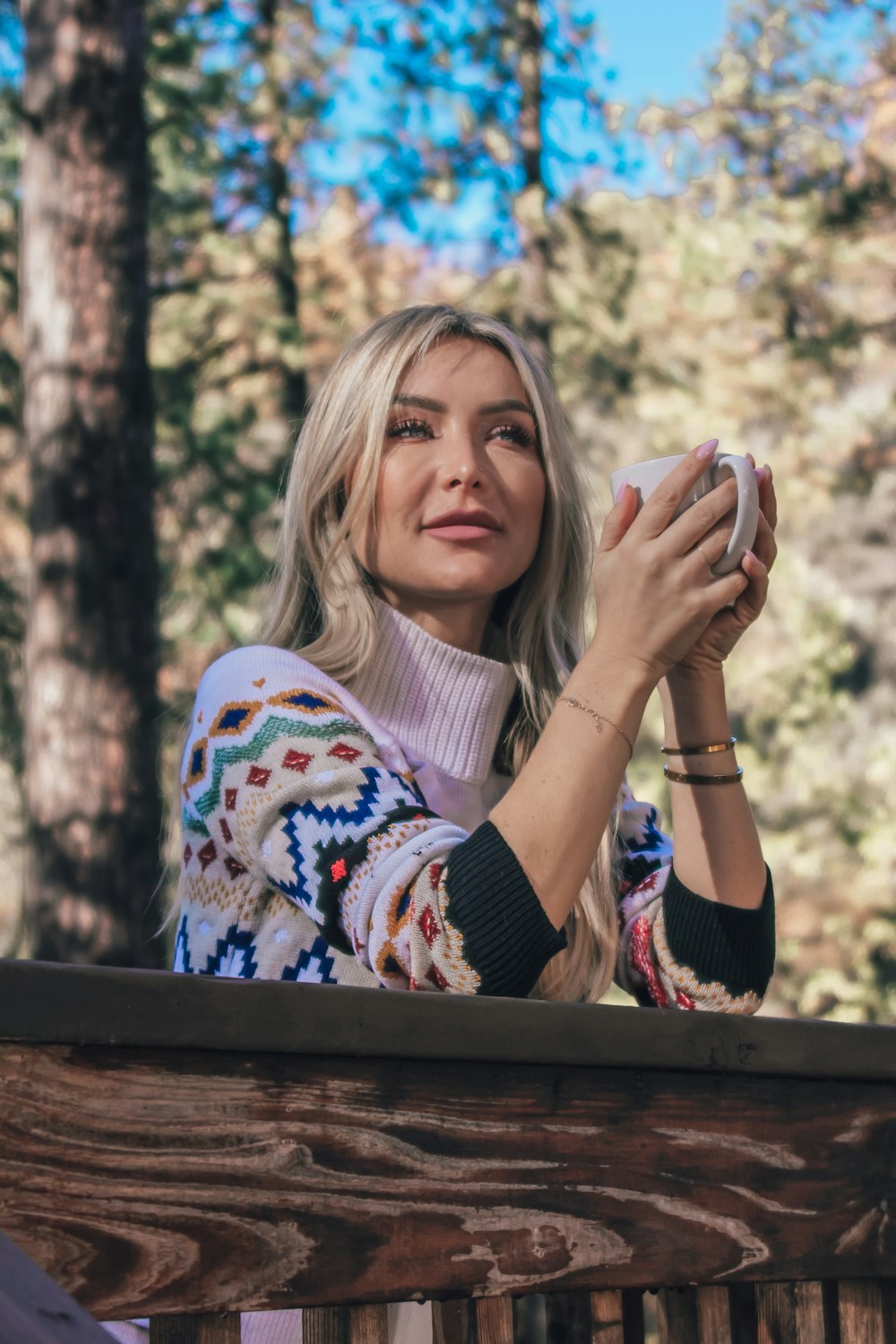 woman in white and blue sweater covering her face with her hands