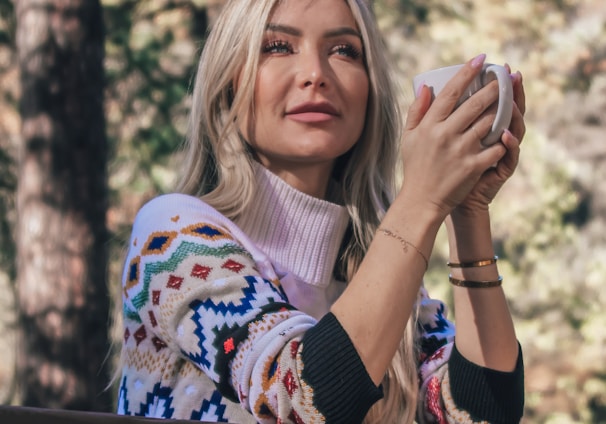 woman in white and blue sweater covering her face with her hands