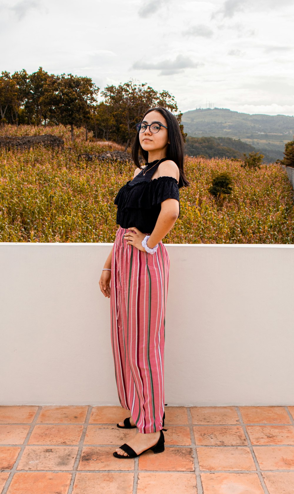 woman in black shirt and pink and white striped skirt standing on white concrete wall during