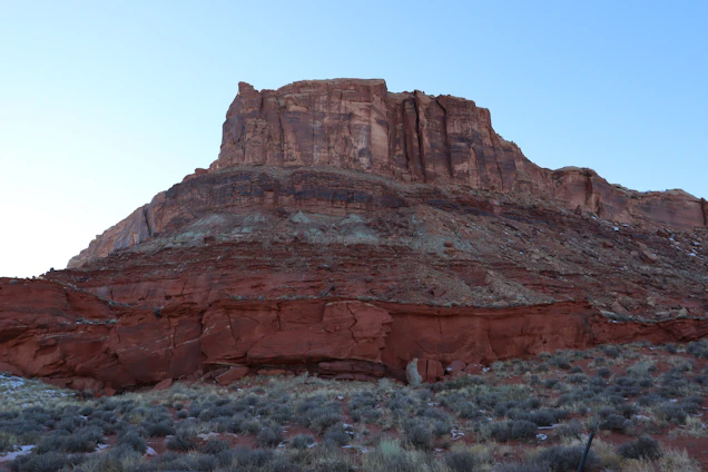 A sunlit mesa with layered rock formations under a clear blue sky, inviting exploration and calm.
