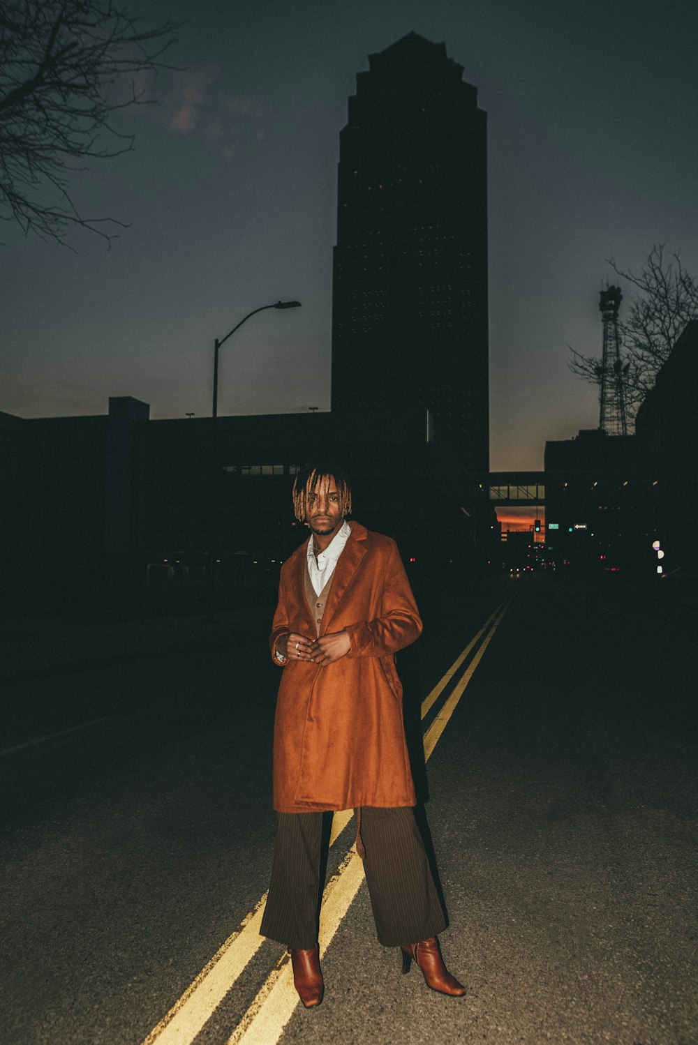 woman in brown coat standing on road during night time