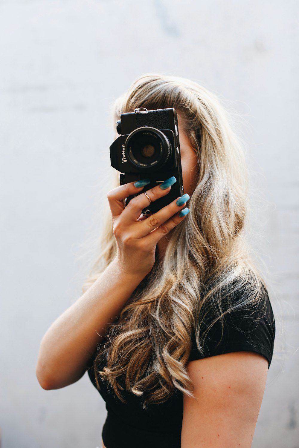 woman in black shirt holding black and silver camera
