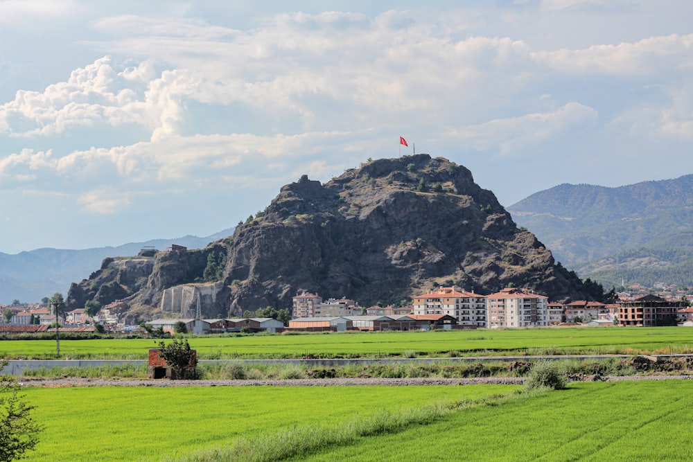 green grass field near mountain under white clouds during daytime