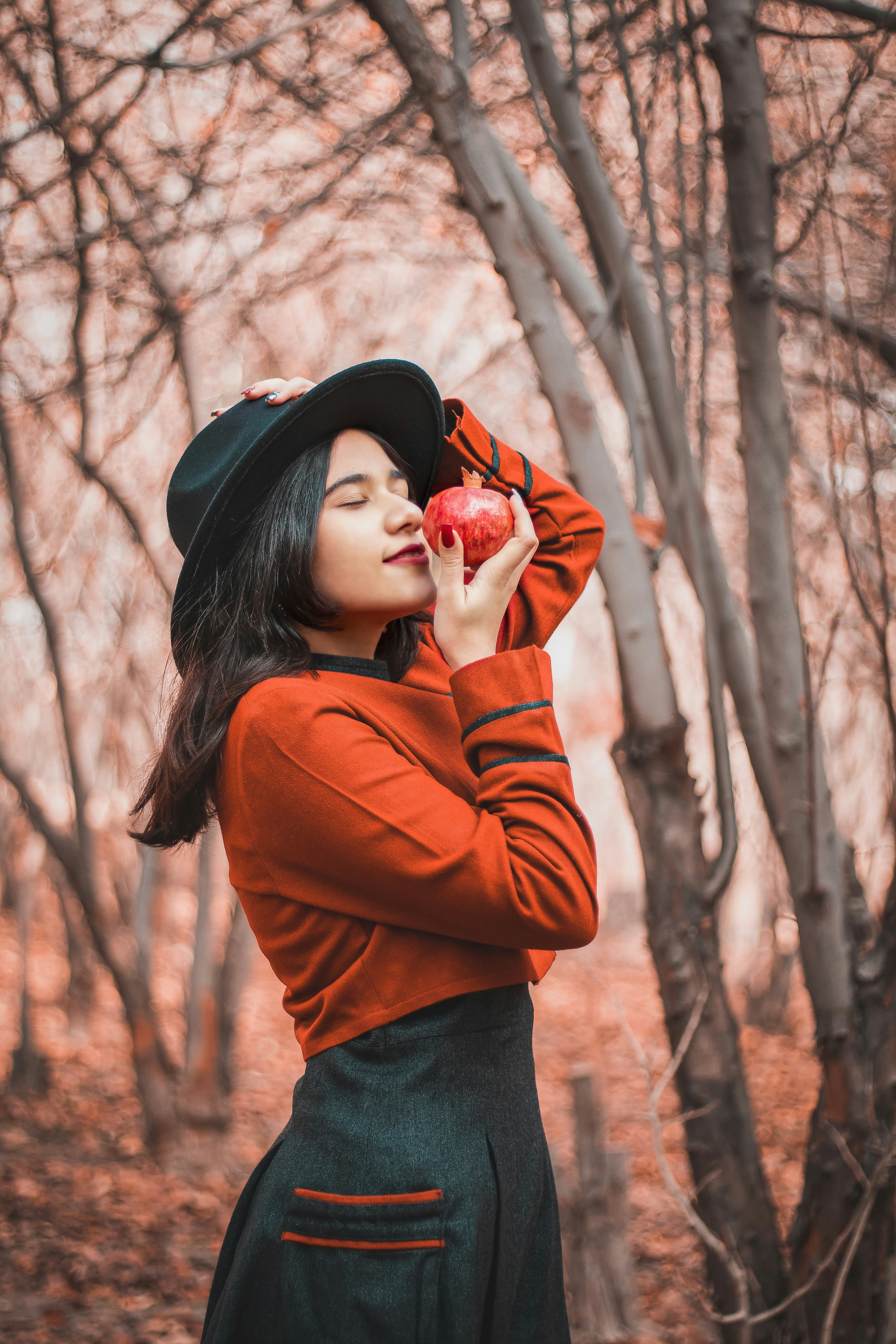 woman in brown long sleeved shirt and black hat standing near bare trees during daytime