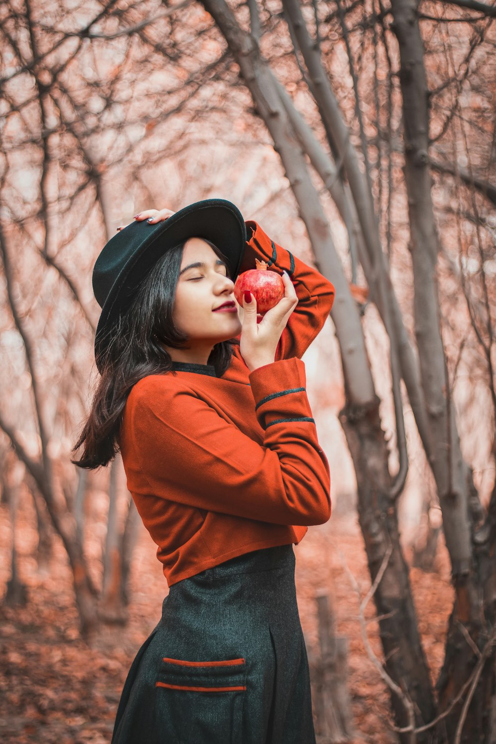 woman in brown long sleeved shirt and black hat standing near bare trees during daytime