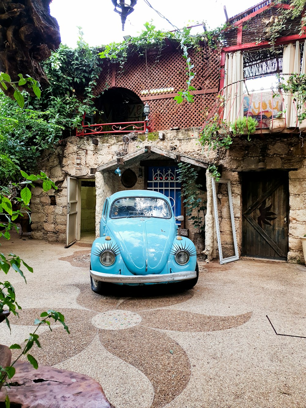 blue volkswagen beetle parked beside brown brick building