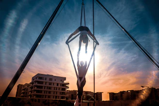 Performers soaring through flames suspended midair against a dusky Wichita sky.
