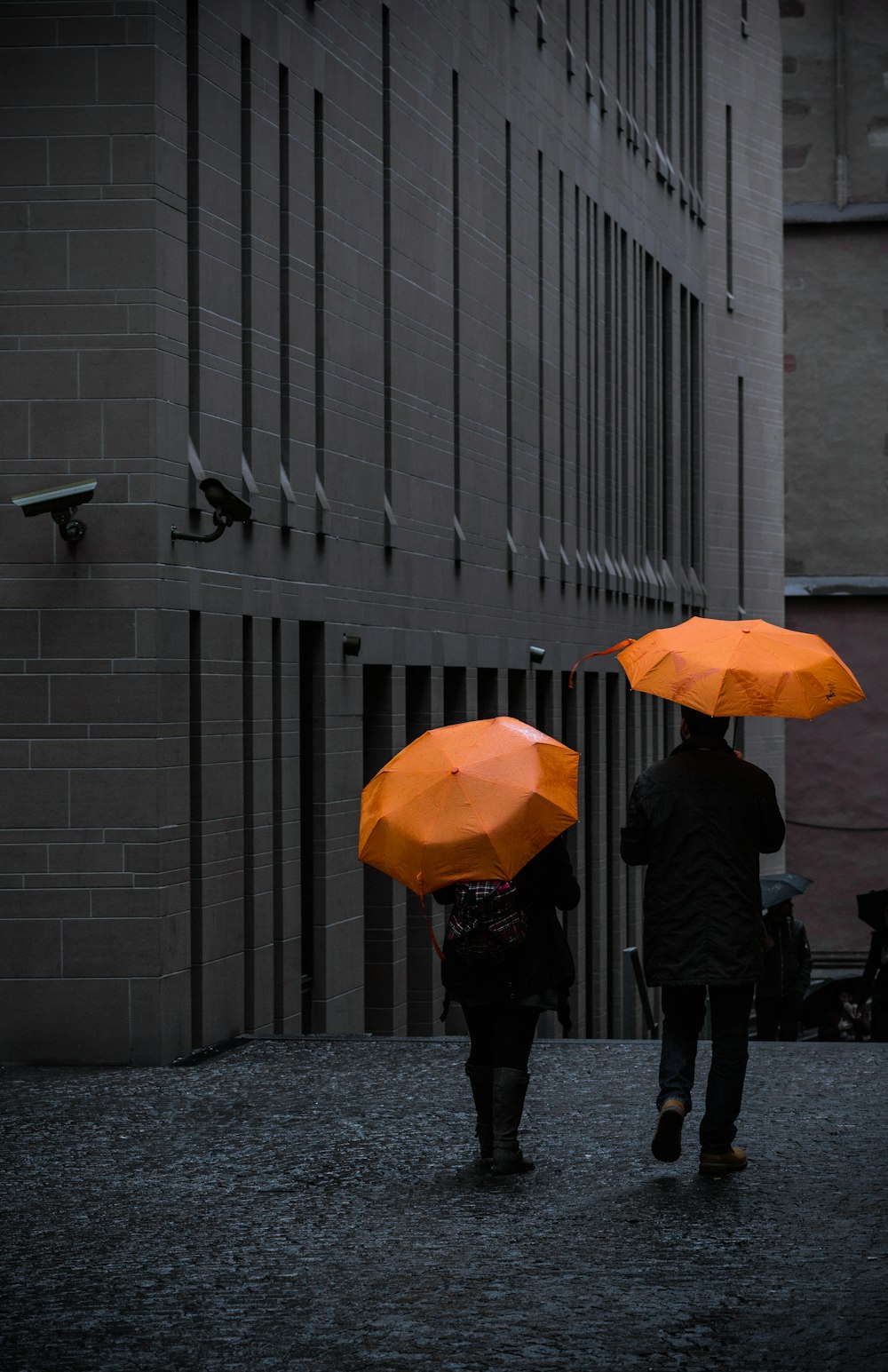 uomo in giacca nera che tiene l'ombrello che cammina sul marciapiede durante il giorno
