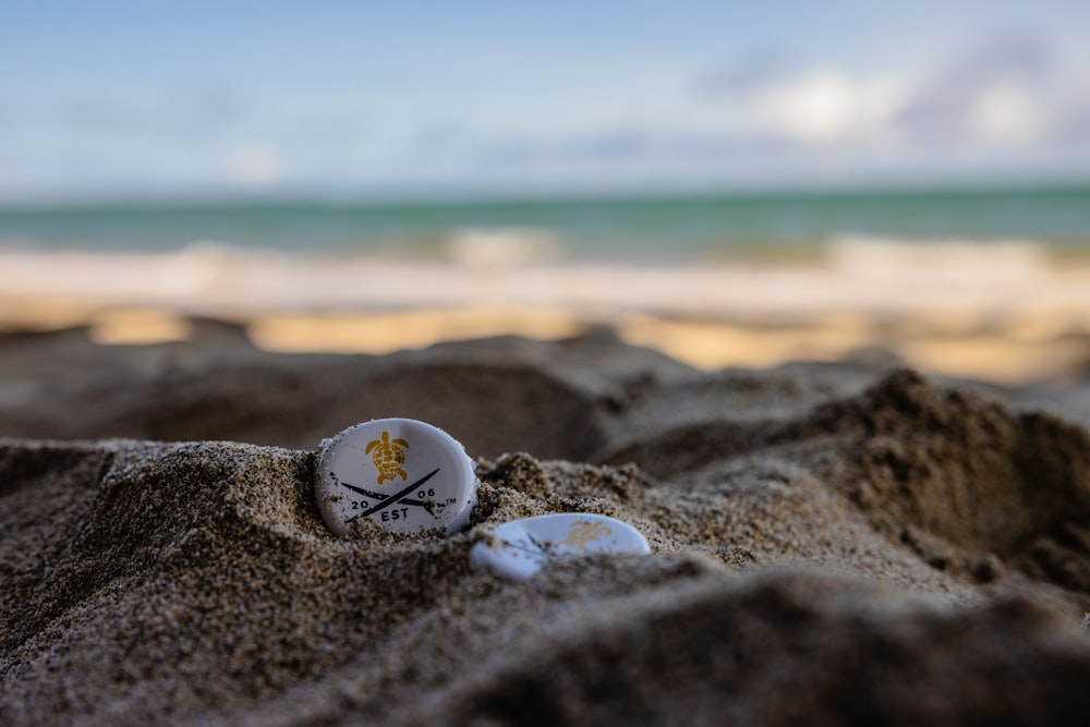 white and black round ornament on brown sand near sea during daytime