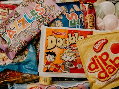 A collection of colorful candy packaging, including brands like Jazzles, Double Dip, and Dip Dab. The variety of packaging features playful designs and vibrant colors.