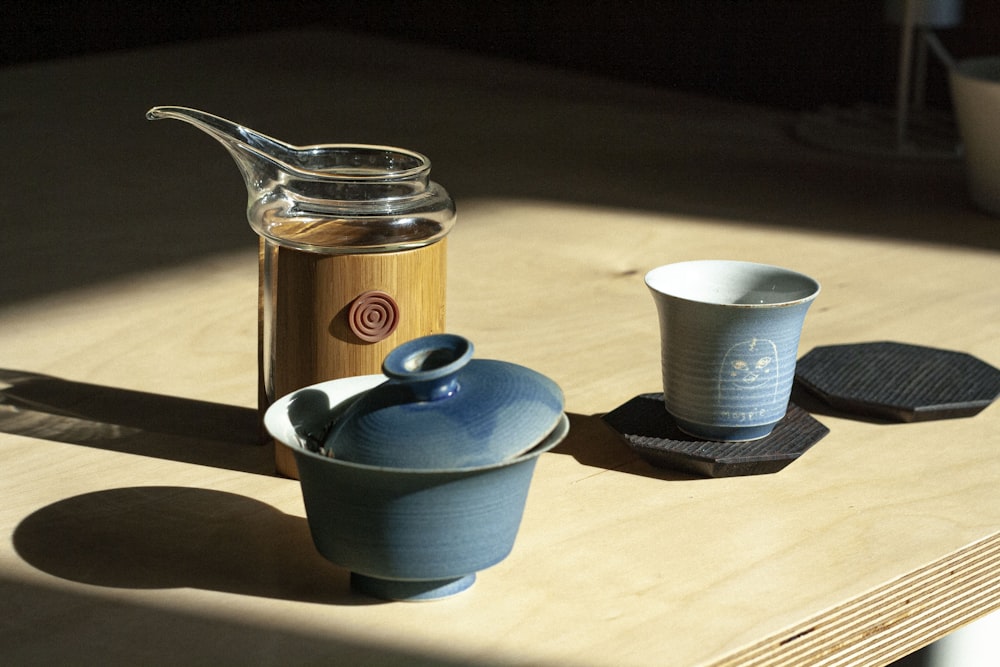 Teiera in ceramica blu accanto a tazza in ceramica bianca su tavolo in legno marrone