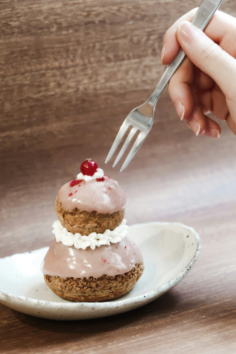 a person is holding a fork over a cupcake on a plate