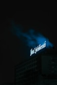 A cinematic drone shot of a stylish business venue with neon blue signage glowing against a dark cityscape.