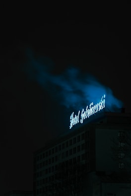 A cinematic drone shot of a stylish business venue with neon blue signage glowing against a dark cityscape.