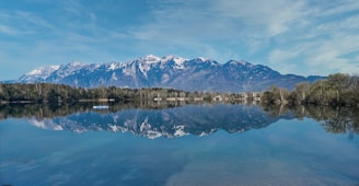 A serene lake reflecting snow-capped mountains during early morning light.
