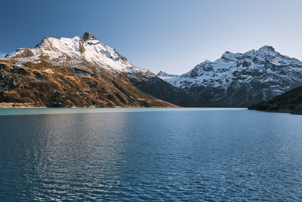 body of water near snow covered mountain during daytime