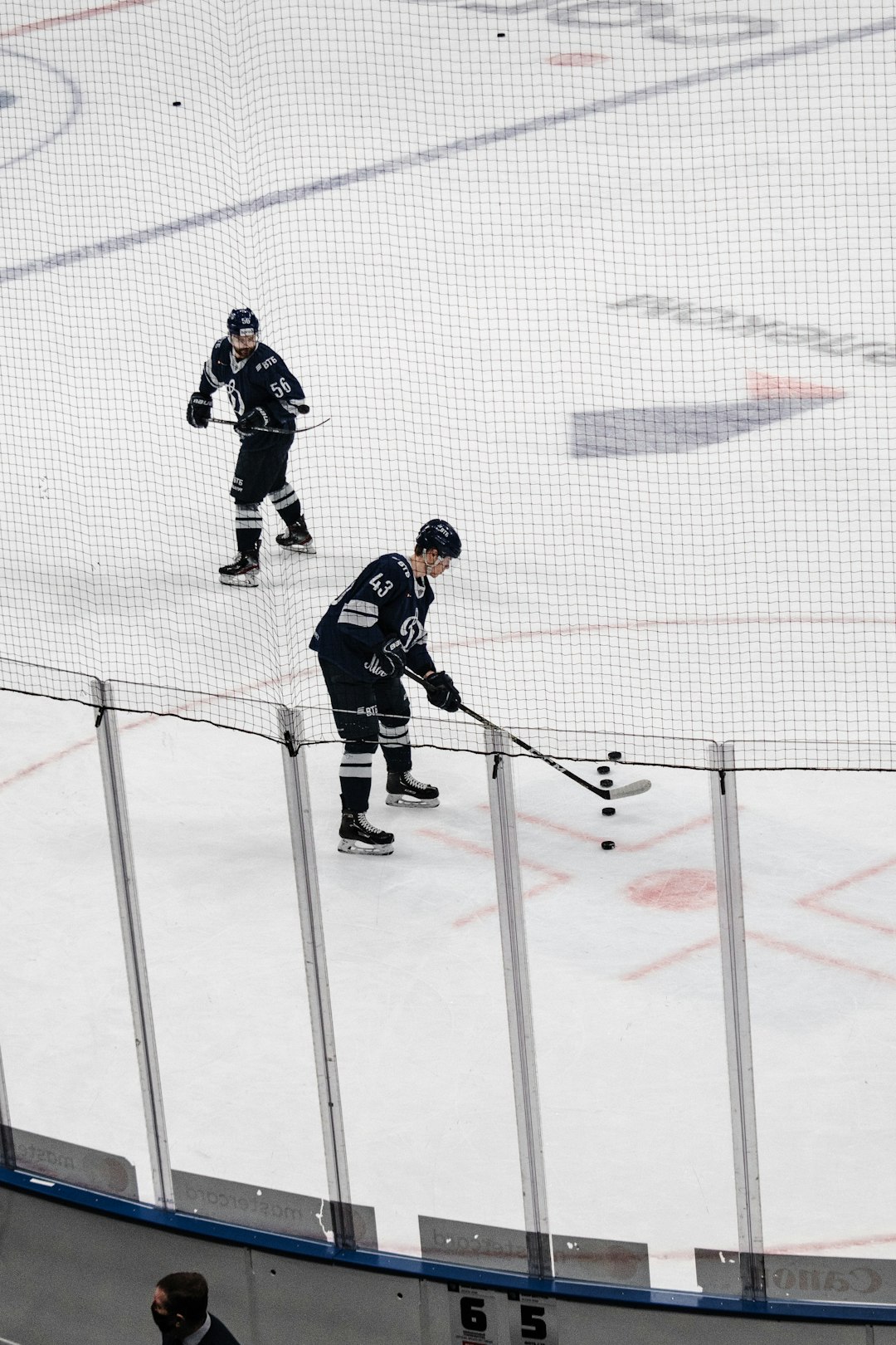 man in black ice hockey jersey shirt and black helmet riding on ice hockey stick