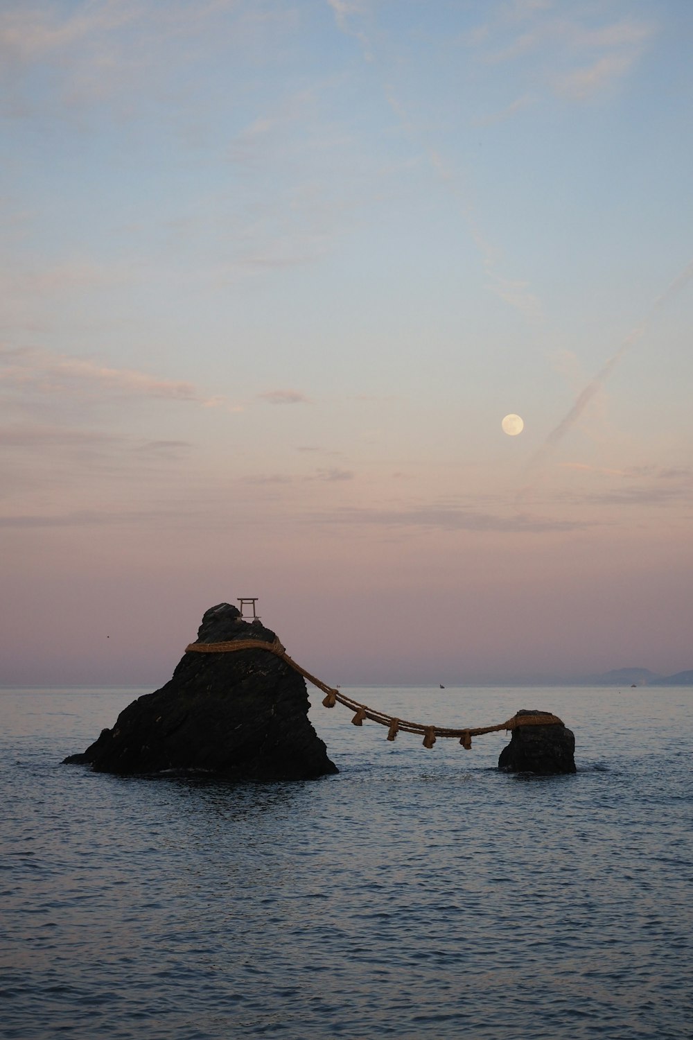 silhouette of rock formation on sea during sunset