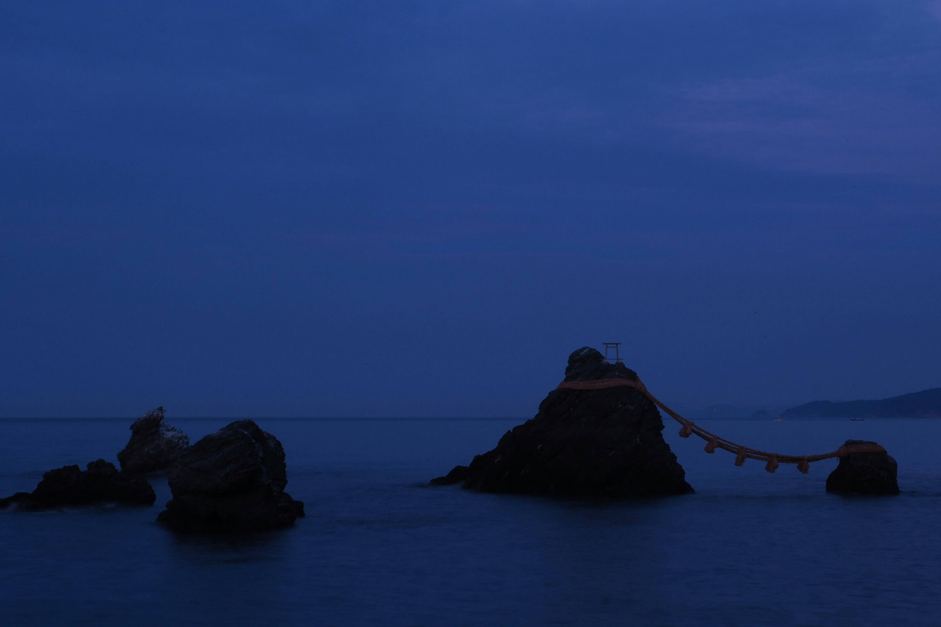 silhouette of rock formation on body of water during night time