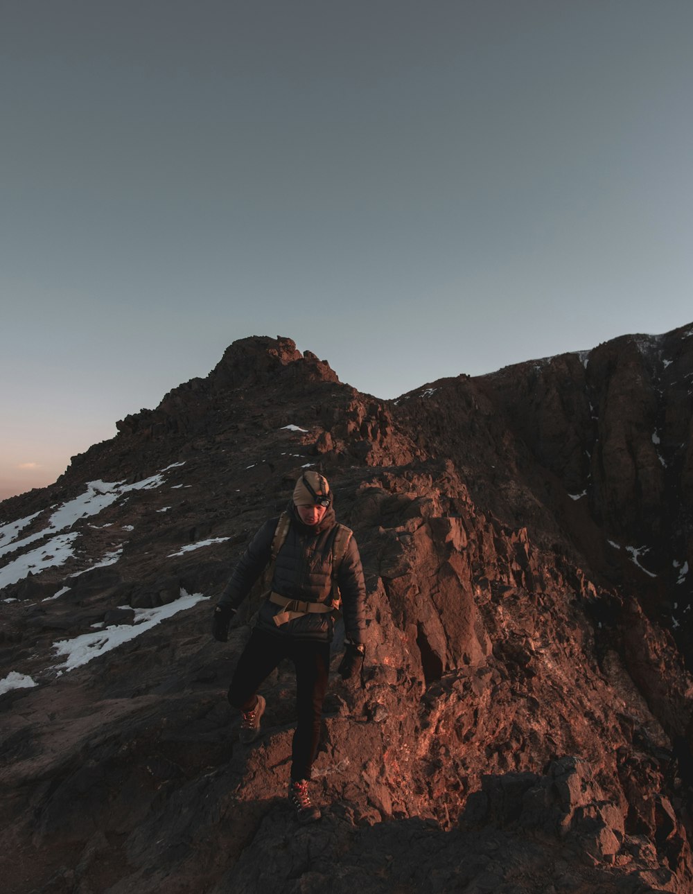 man in black jacket standing on brown rock formation during daytime