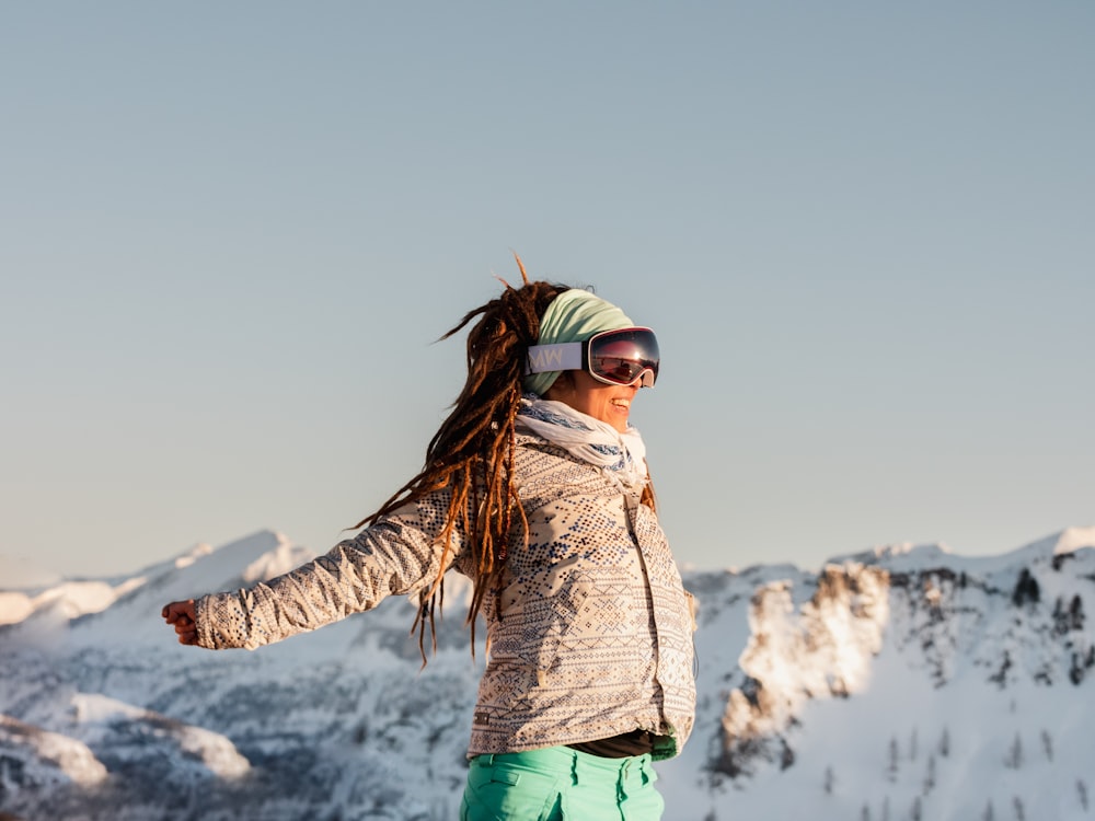 woman in brown jacket and green pants standing on snow covered ground during daytime