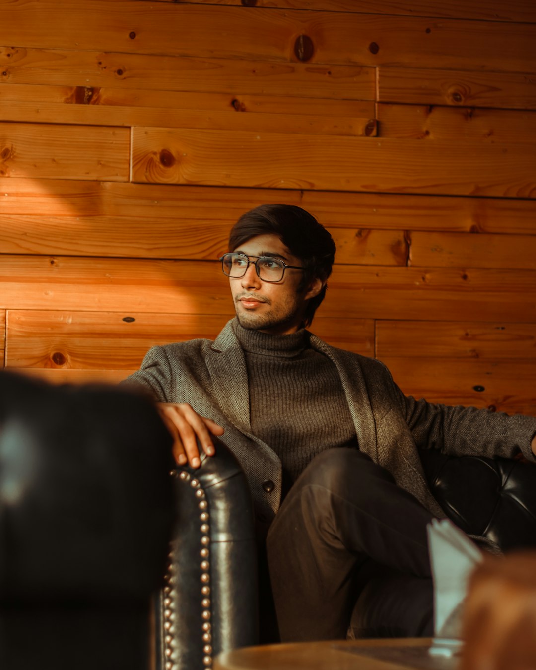 man in gray sweater sitting on black leather couch