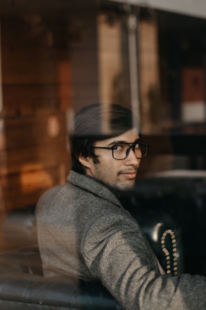 man in gray coat wearing black framed eyeglasses