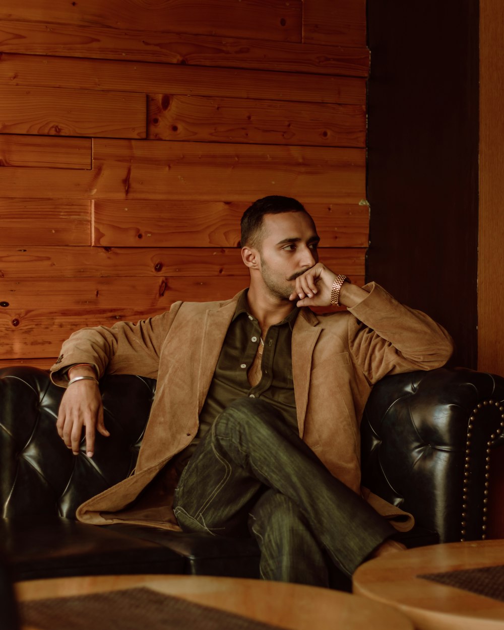 man in brown leather jacket sitting on black leather armchair