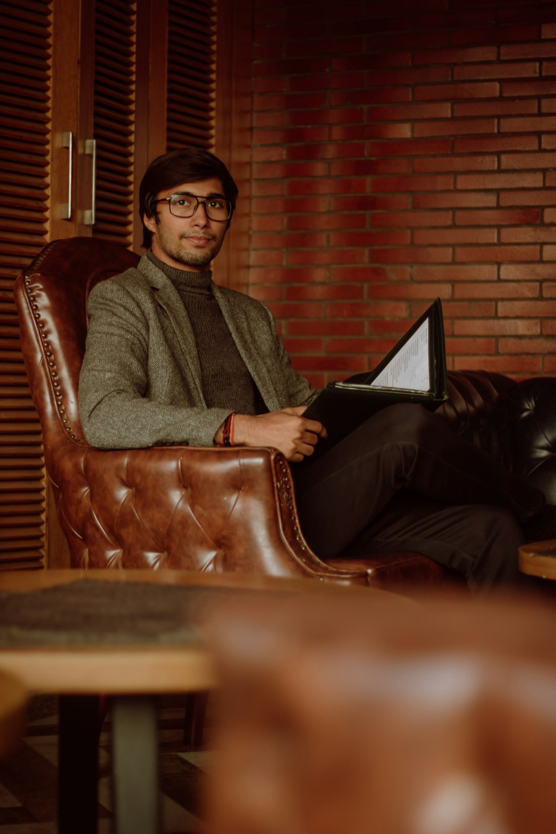 man in gray sweater sitting on brown leather armchair