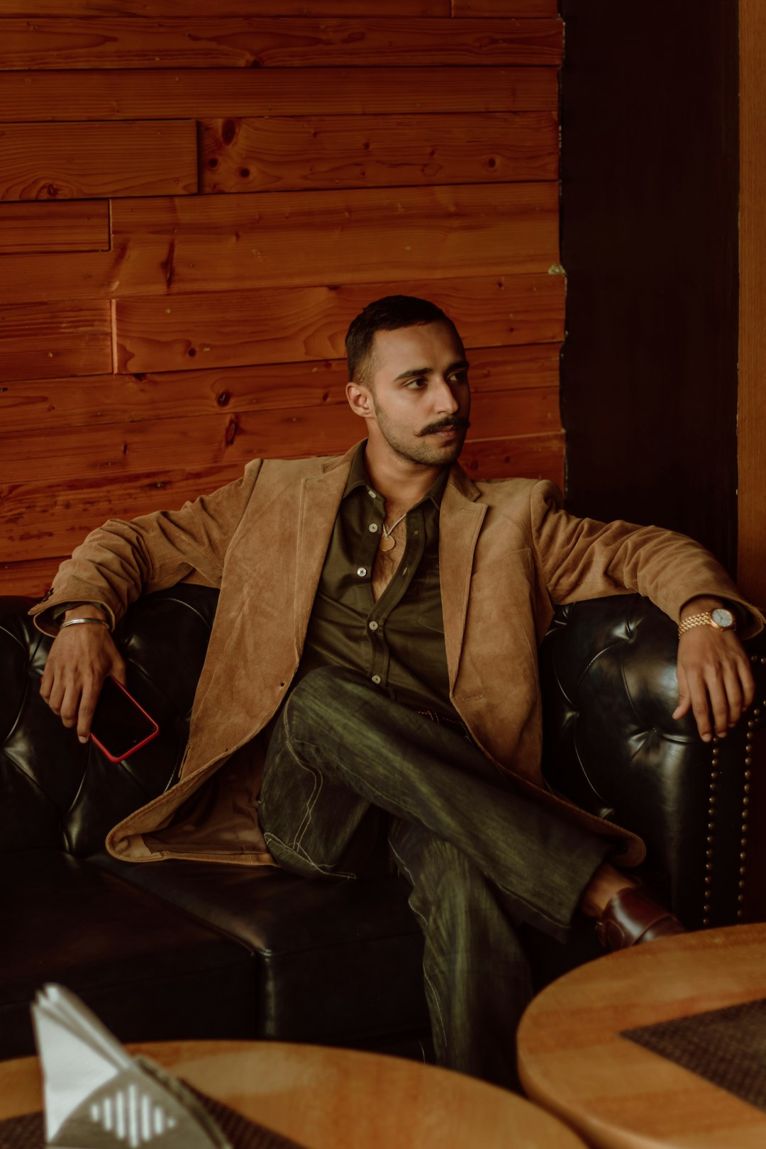 man in brown suit sitting on black leather armchair