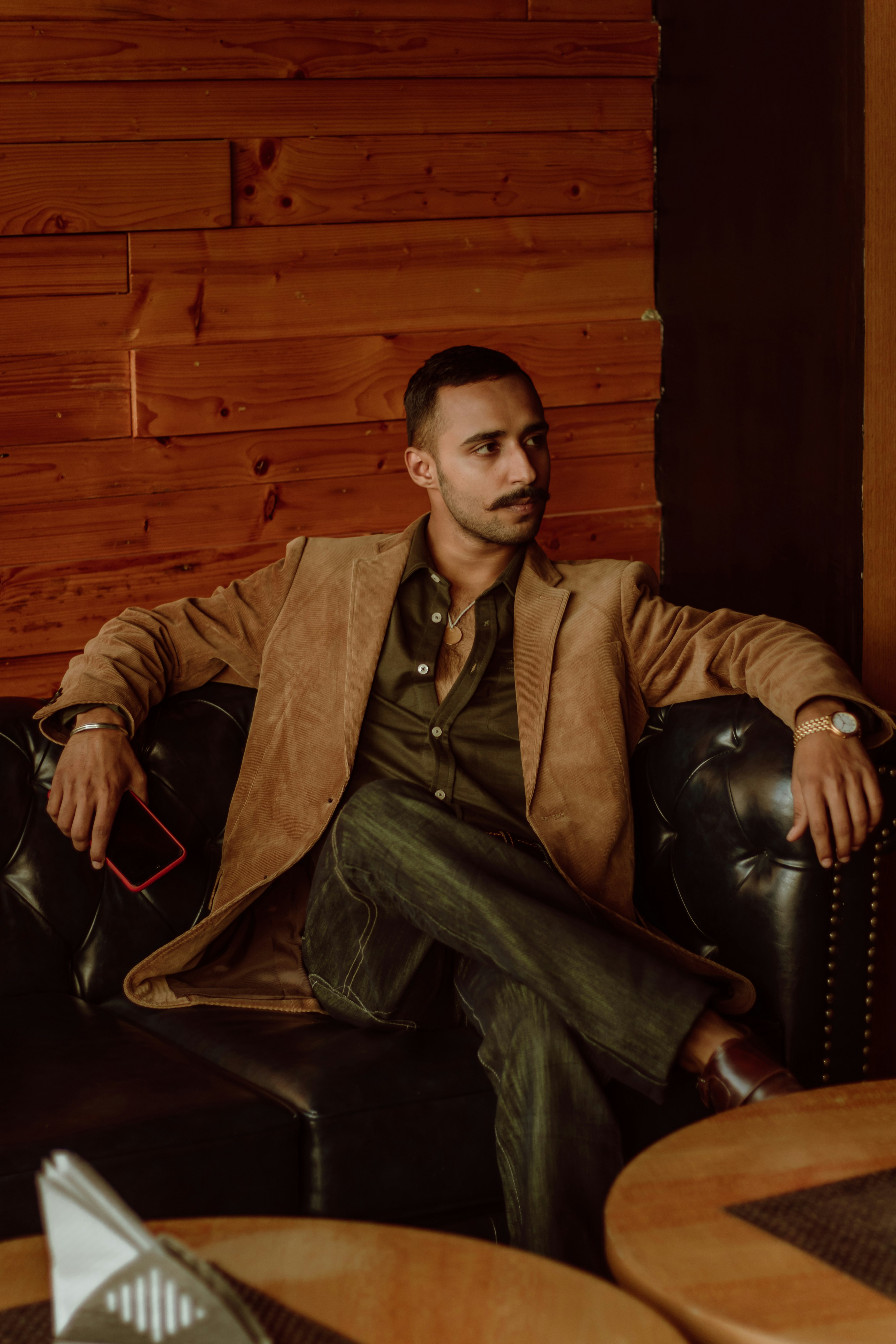 man in brown suit sitting on black leather armchair