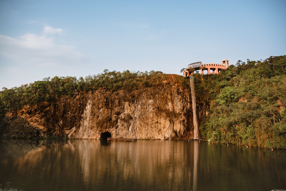 white and red house on brown rock formation beside body of water during daytime